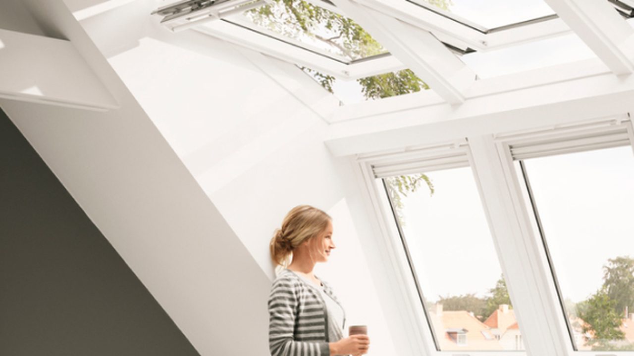 Lichte woonkamer onder een schuin dak met meerdere grote VELUX dakramen — Hoe kies je de juiste dakraam? Maten, materiaal & types