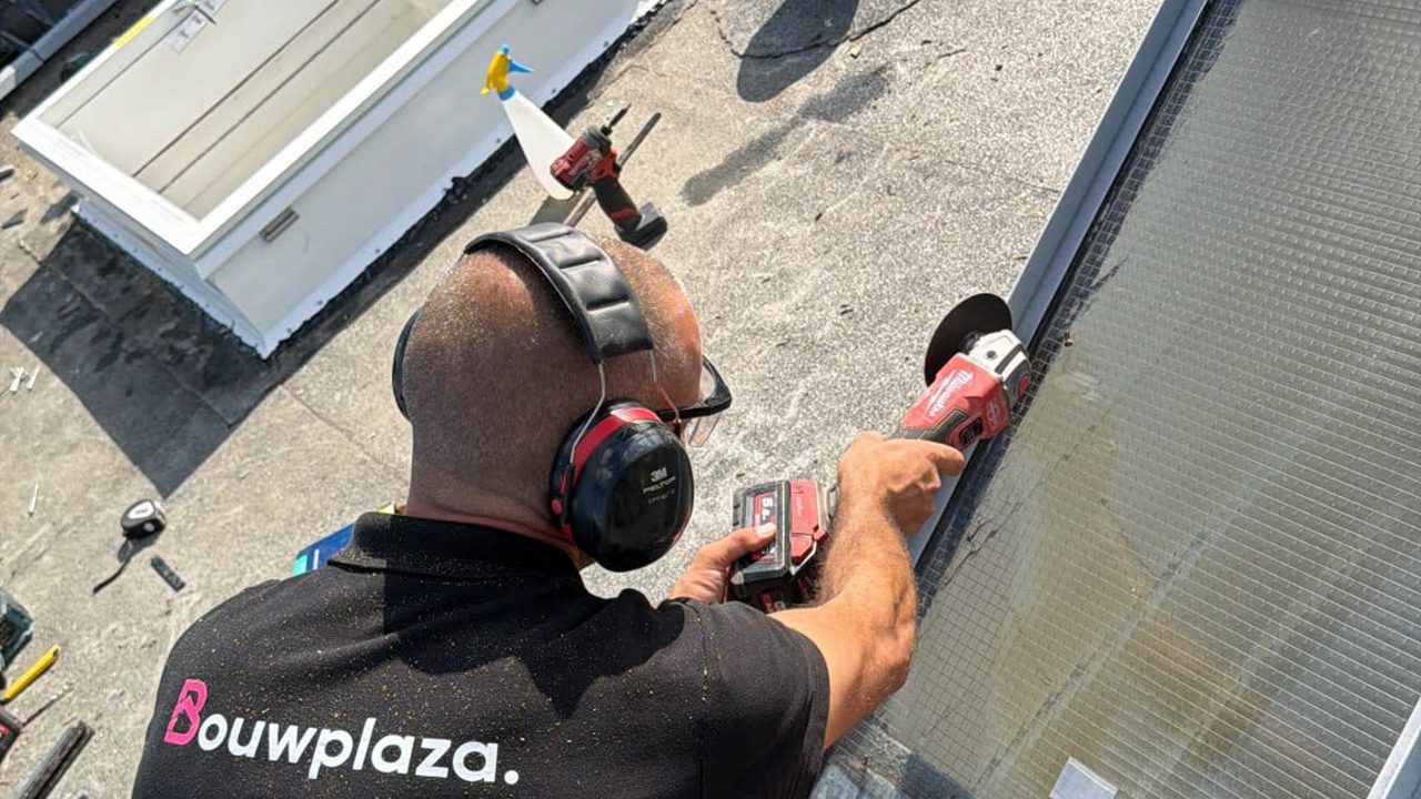 Bouwplaza-monteur zaagt een dakopening op een plat dak voor een nieuw daglichtsysteem — Platdak dakraam: alle mogelijkheden voor uw platte dak
