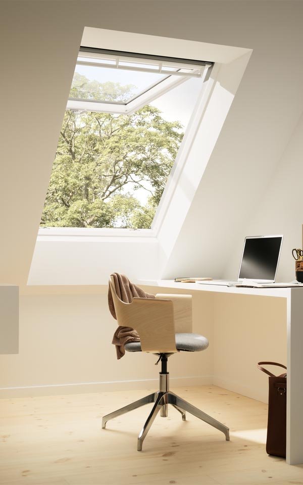 Geopend VELUX uitzettuimelvenster in een lichte zolderkamer met bureau